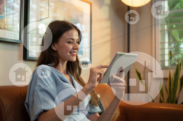 A woman smiling at her iPad while buying real estate online, with small images of a house in the foreground